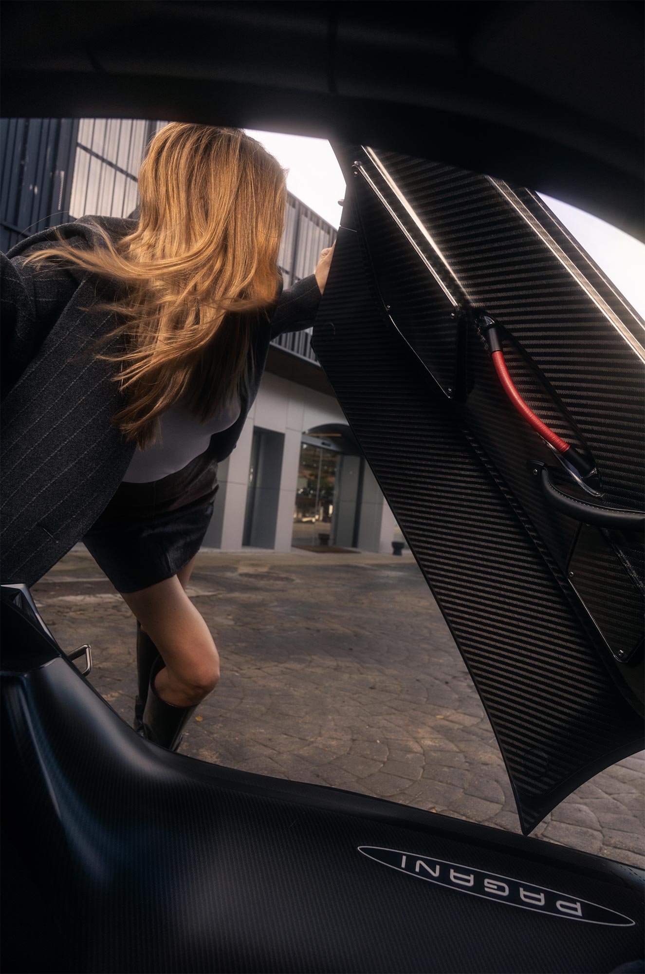 Carmen opening the eagle style doors of a supercar