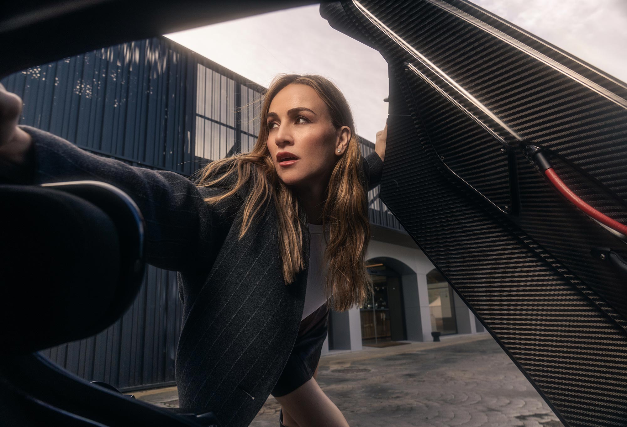 Carmen standing in the doorway of a supercar
